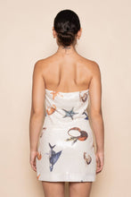Load image into Gallery viewer, Model wearing a strapless white sequin mini dress featuring ocean-inspired seashell, starfish, and seahorse embellishments in a fitted bodycon silhouette.
