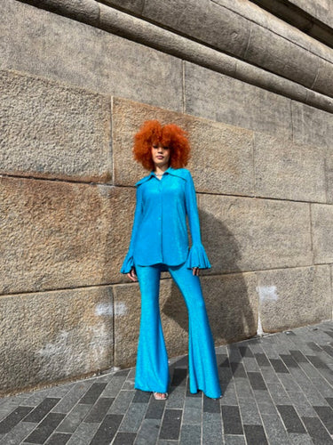 Person wearing a blue outfit standing on a stone pavement.