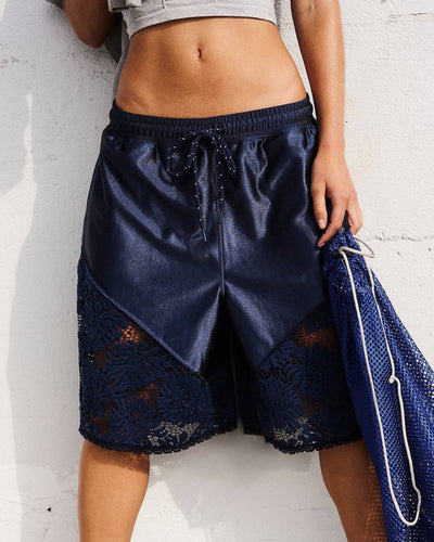 Navy blue shorts with lace detailing worn by a person against a white background