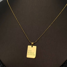 Load image into Gallery viewer, 18K gold-plated rectangular pendant necklace engraved with The World Is Yours on a delicate gold chain.
