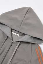 Load image into Gallery viewer, Dark gray fitted zip-up hoodie with orange sleeve stripes, oversized hood and dramatic layered ruffle bell sleeves.
