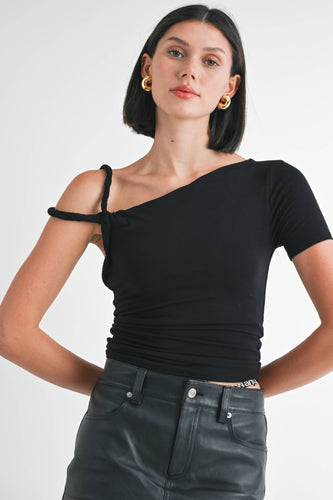 Woman wearing a black one-shoulder top and black leather pants on a white background