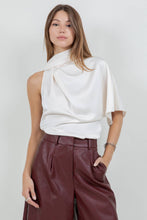 Load image into Gallery viewer, Woman wearing an ivory satin one-shoulder asymmetrical blouse with draped scarf detail paired with burgundy leather pants
