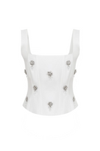 Load image into Gallery viewer, White structured bustier top featuring wide straps and multiple crystal floral embellishments across the front, photographed on a white background.
