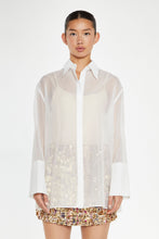 Load image into Gallery viewer, Introducing the White Organza Long Sleeve Button Down Shirt, an elegant and versatile staple for your wardrobe. Crafted from delicate organza, this chic piece effortlessly elevates any outfit. Wear it buttoned up for a polished look or layered over a bralette for a modern, trendy twist. Perfect for any occasion, from the office to an evening out, this shirt is your go-to for instant sophistication.
