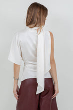Load image into Gallery viewer, Woman wearing an ivory satin one-shoulder asymmetrical blouse with draped scarf detail paired with burgundy leather pants

