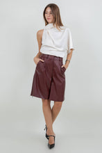 Load image into Gallery viewer, Woman wearing an ivory satin one-shoulder asymmetrical blouse with draped scarf detail paired with burgundy leather pants
