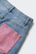 Load image into Gallery viewer, Close-up of light-wash denim jeans featuring sparkling pink crystal embellished back pocket detail.
