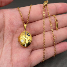 Load image into Gallery viewer, 18K gold-plated oval celestial locket necklace with blue enamel crescent moon, starburst details and sparkling cubic zirconia accents.
