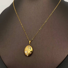 Load image into Gallery viewer, 18K gold-plated oval celestial locket necklace with blue enamel crescent moon, starburst details and sparkling cubic zirconia accents.
