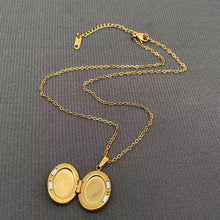 Load image into Gallery viewer, 18K gold-plated oval celestial locket necklace with blue enamel crescent moon, starburst details and sparkling cubic zirconia accents.
