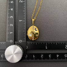 Load image into Gallery viewer, 18K gold-plated oval celestial locket necklace with blue enamel crescent moon, starburst details and sparkling cubic zirconia accents.
