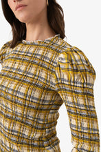 Load image into Gallery viewer, Yellow plaid smocked blouse with ruffle trim and long sleeves worn by model.
