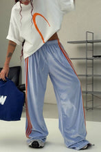 Load image into Gallery viewer, Powder blue velour wide-leg sweatpants featuring a relaxed silhouette, elastic waistband, and contrasting orange racing stripes.
