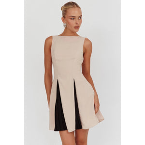 A sleeveless beige mini dress featuring a boat neckline and contrast black accents peeking through the pleats, creating a chic and versatile look suitable for any occasion. 