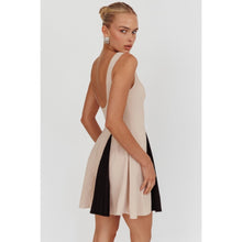 Load image into Gallery viewer, A sleeveless beige mini dress featuring a boat neckline and contrast black accents peeking through the pleats, creating a chic and versatile look suitable for any occasion. 
