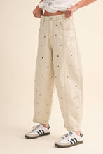 Load image into Gallery viewer, Model wearing cream barrel-leg jeans embellished with silver stud details throughout, featuring a high-rise waist and relaxed statement silhouette.
