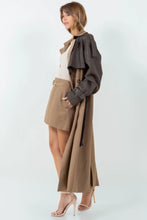 Load image into Gallery viewer, A long brown trench coat featuring a mix of vegan leather and traditional trench materials, offering a unique and chic style. 
