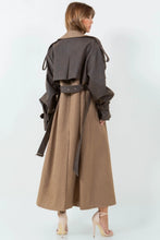 Load image into Gallery viewer, A long brown trench coat featuring a mix of vegan leather and traditional trench materials, offering a unique and chic style. 
