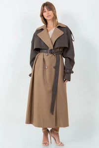 A long brown trench coat featuring a mix of vegan leather and traditional trench materials, offering a unique and chic style. 