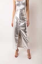 Load image into Gallery viewer, Our Silver Metallic Maxi Skirt is the skirt of the season! This high waisted maxi skirt in faux leather metallic fabric is set to become your wardrobe staple! Tailored to perfection this skirt fits like a dream and has a front slit and front fly fastening. Equally great with heels or flats this is definitely going to be the perfect summer wardrobe staple! Remix it with a chunky knit and boots in the Fall and Winter seasons.
