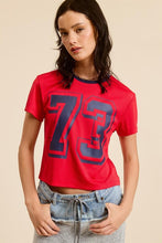 Load image into Gallery viewer, Unleash your sporty side with our Crop Jersey Tee Number 73! This baby tee blends comfort and style, featuring a soft jersey fabric that hugs your body just right. The bold number 73 adds a touch of athletic flair, making it perfect for casual outings or an active day out. Pair it with high-waisted jeans or your favorite shorts for a trendy, effortless look. Elevate your wardrobe with this must-have sporty staple!
