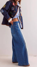 Load image into Gallery viewer, Person wearing a denim jacket with patches and wide-leg jeans on a white background
