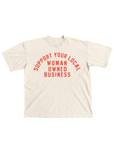 Load image into Gallery viewer, Cream 100% cotton graphic T-shirt with bold red lettering reading "Support Your Local Woman-Owned Business," shown on a model wearing the relaxed-fit tee.
