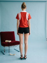 Load image into Gallery viewer, Red short-sleeve polo top with white contrast collar and panel detailing, styled with black shorts for a sporty chic look.
