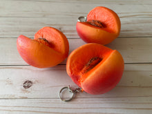 Load image into Gallery viewer, Realistic peach-shaped coin purse with zipper, keychain ring, and bag charm attachment displayed on a wood background.
