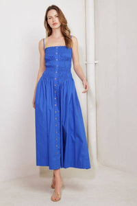 Woman wearing a blue dress with buttons against a white background