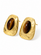Load image into Gallery viewer, Oversized textured gold-tone statement earrings with irregular rounded-square frames and large glossy brown oval cabochon centers.
