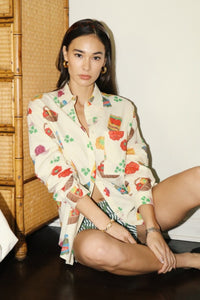 Cream-colored button-up shirt with colorful grocery and snack print, featuring short sleeves and a relaxed fit — perfect for playful summer style. Matching printed shorts sold separately. Fun, foodie-inspired fashion exclusively at Glam Expressway.