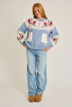 Load image into Gallery viewer, A light blue and cream color-block cardigan sweater featuring a vibrant floral intarsia knit design, seamlessly blending the comfort of a sweater with the structure of a cardigan jacket for effortless style. 
