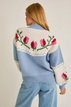 Load image into Gallery viewer, A light blue and cream color-block cardigan sweater featuring a vibrant floral intarsia knit design, seamlessly blending the comfort of a sweater with the structure of a cardigan jacket for effortless style. 
