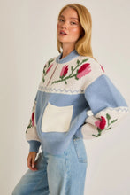 Load image into Gallery viewer, A light blue and cream color-block cardigan sweater featuring a vibrant floral intarsia knit design, seamlessly blending the comfort of a sweater with the structure of a cardigan jacket for effortless style. 
