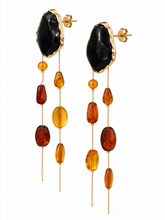 Load image into Gallery viewer, Extra-long statement earrings with oversized glossy black studs and cascading gold-tone chains accented with translucent amber, honey and cognac-colored beads.
