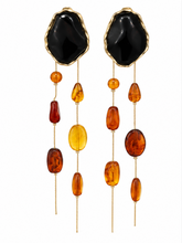 Load image into Gallery viewer, Extra-long statement earrings with oversized glossy black studs and cascading gold-tone chains accented with translucent amber, honey and cognac-colored beads.
