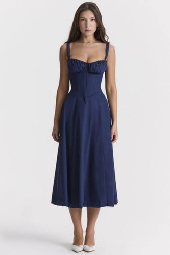 A model showcases a navy blue corset midi dress with a plait front, sleeveless design, and two shoulder straps, crafted from light, breathable fabric for a comfortable yet elegant look. 