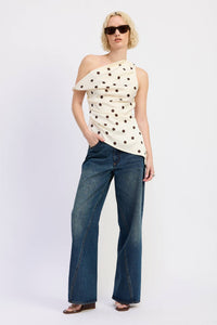 Woman wearing a polka dot top and blue jeans on a white background