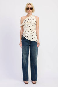Woman wearing a polka dot top and blue jeans on a white background