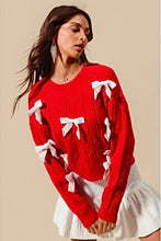 Load image into Gallery viewer, Add a playful pop of color to your wardrobe with our Cherry Red Cable Knit Sweater, adorned with delicate white ribbon bow appliqués! This cozy yet statement-making sweater features a classic cable knit design in a bold red hue, with charming white bows adding a whimsical touch. Perfect for pairing with jeans or a skirt, this sweater will keep you warm and stylish all season long. Available in sizes S to XL for the perfect fit!
