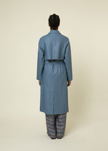 Load image into Gallery viewer, Our butter soft, light blue, vegan leather trench coat has all the standard touches that make a trench coat great like long sleeves, a shirt collar, button closure and a self tie sash belt. This lovely coat is comfortable to wear with full lining and the perfect length. Best of all its retro flair.   Style Tip: Wear our Blue Leather Trench Coat dressed up or down. Our only tip is - never take it off!
